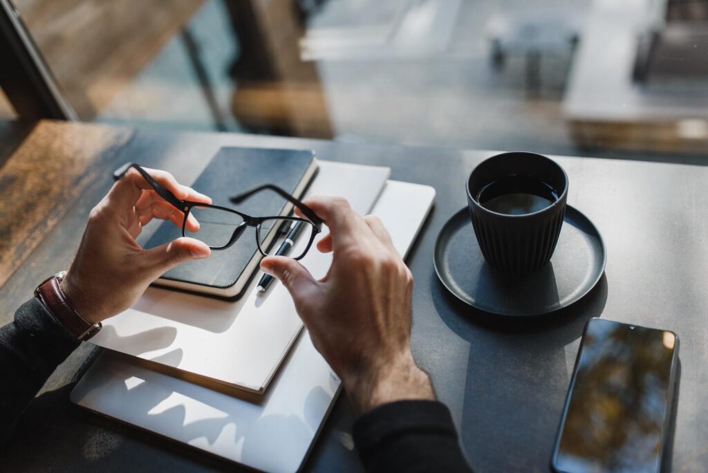 Person holding spectacles on a desk